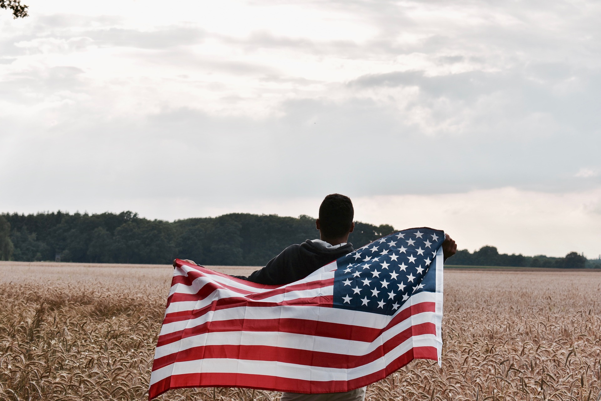 Junger Schwarzer mit Flagge der USA auf Feld
